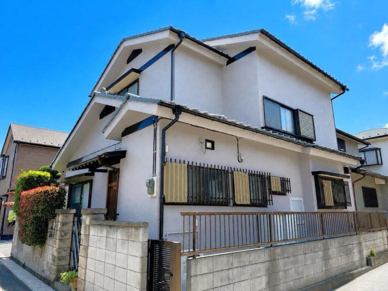 ホワイト系に外壁塗装した2階建て戸建て住宅の施工後の外観。黒い雨樋や窓枠がアクセントになった仕上がり