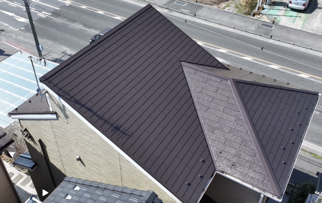 ダークブラウン系に塗装した戸建て住宅の屋根を上空から撮影した施工後の様子